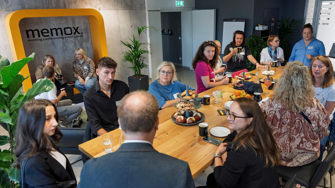 Gruppe sitzt am Brückentisch und spricht miteinander.
