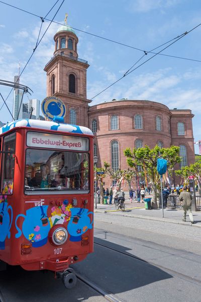 Eine historische Straßenbahn für Stadtrundfahrten steht an der Haltestelle, im Hintergrund die Paulskirche