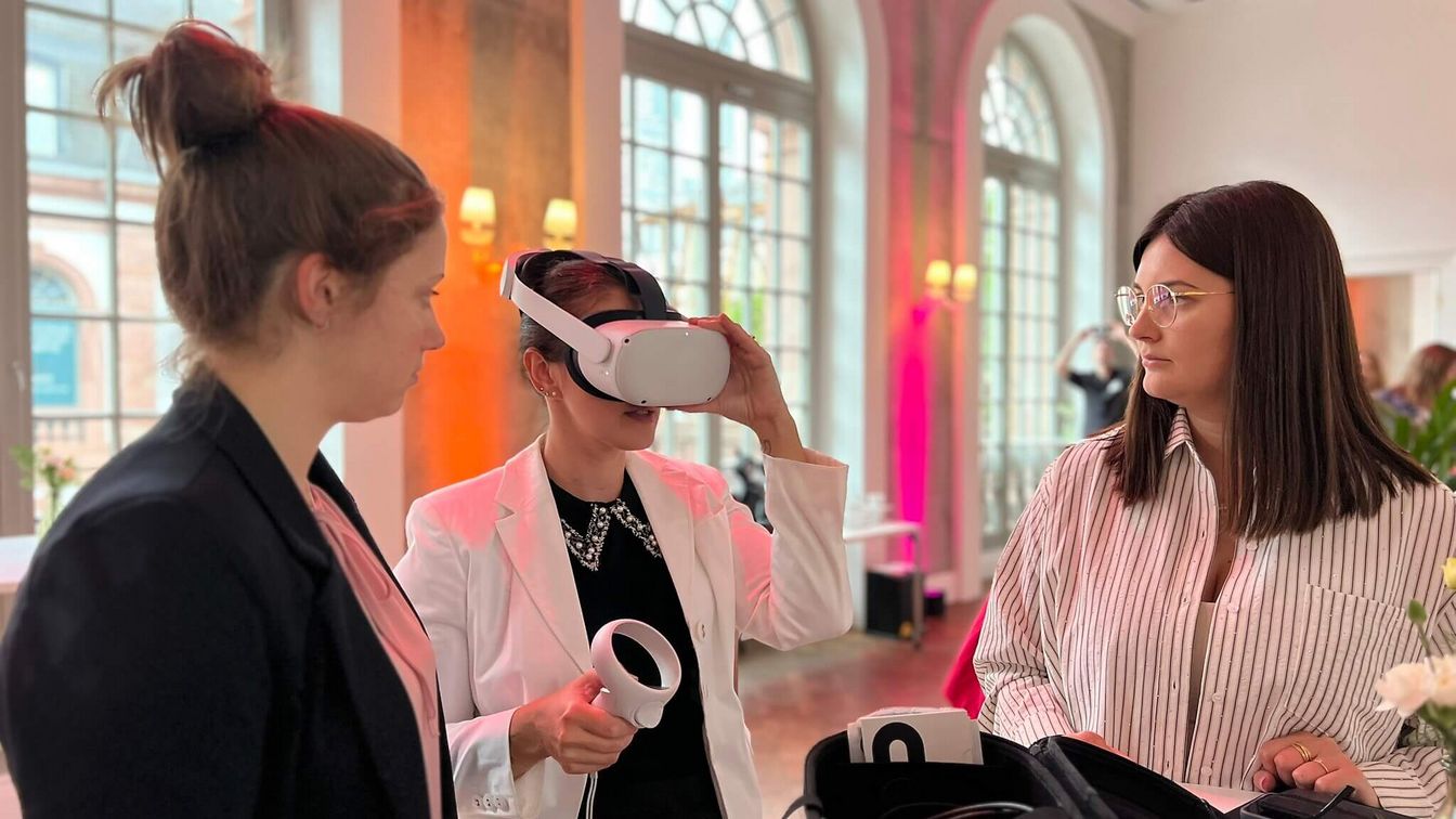 Drei Personen, eine schaut durch eine VR-Brille.