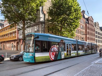 Straßenbahn vor Gebäuden der Frankfurter Neuen Altstadt bei Sonnenschein.