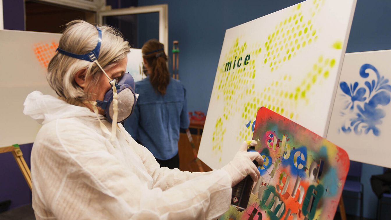 Eine Frau sprayt ein Kunstwerk während eines Graffiti-Workshops.